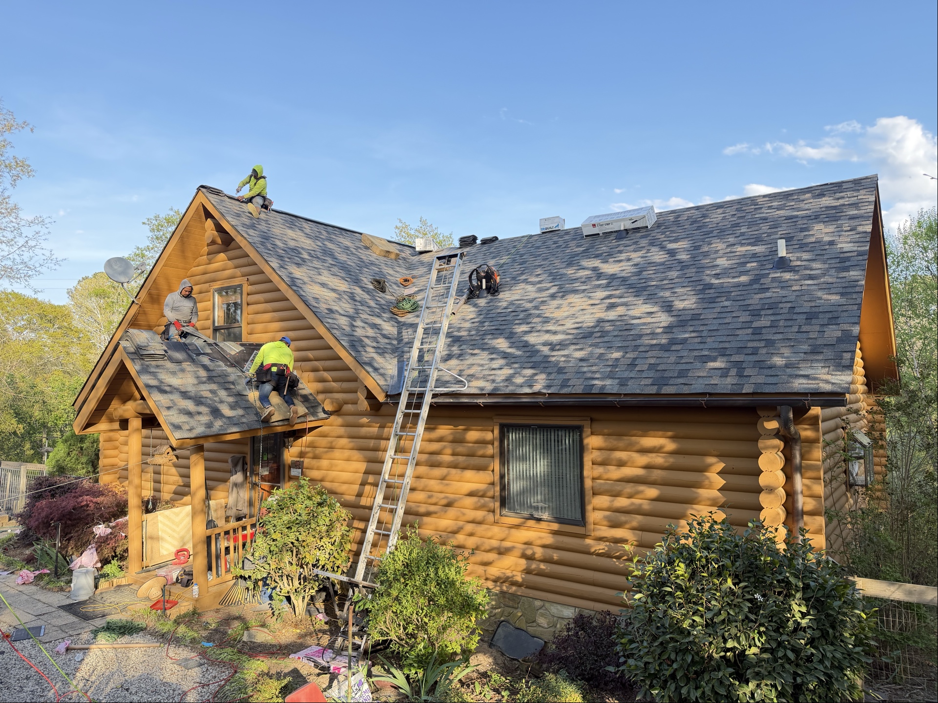 Exterior Genie team installing shingles on a log cabin home