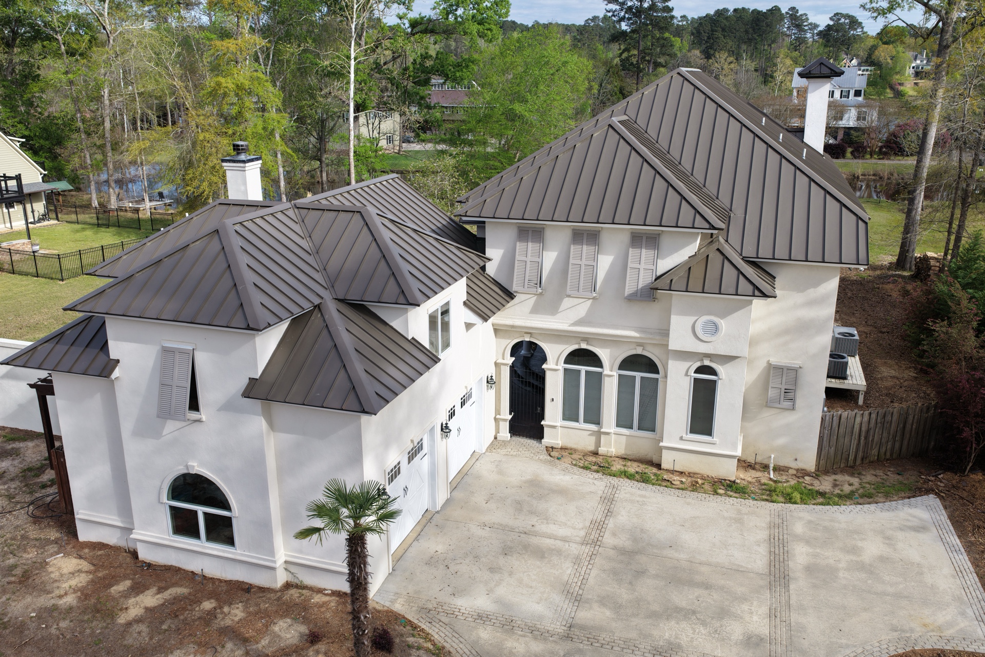 Completed standing seam metal roof on a luxury white stucco home