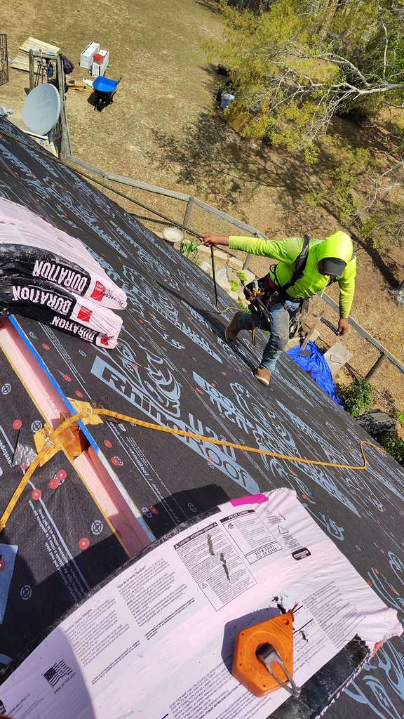 Exterior Genie worker with safety harness installing Owens Corning shingles